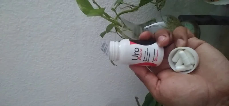 Frasco de Uro Active en la mano de un cliente: etiqueta y cápsulas